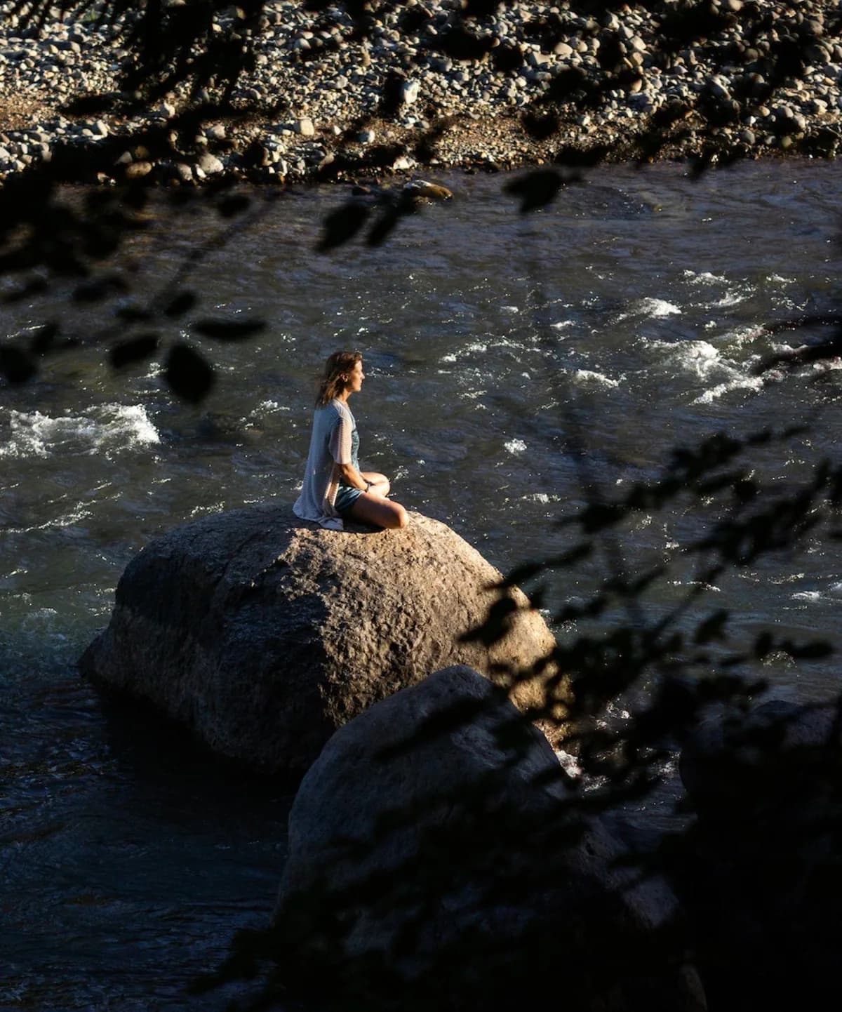 A person meditating beside a rainforest river