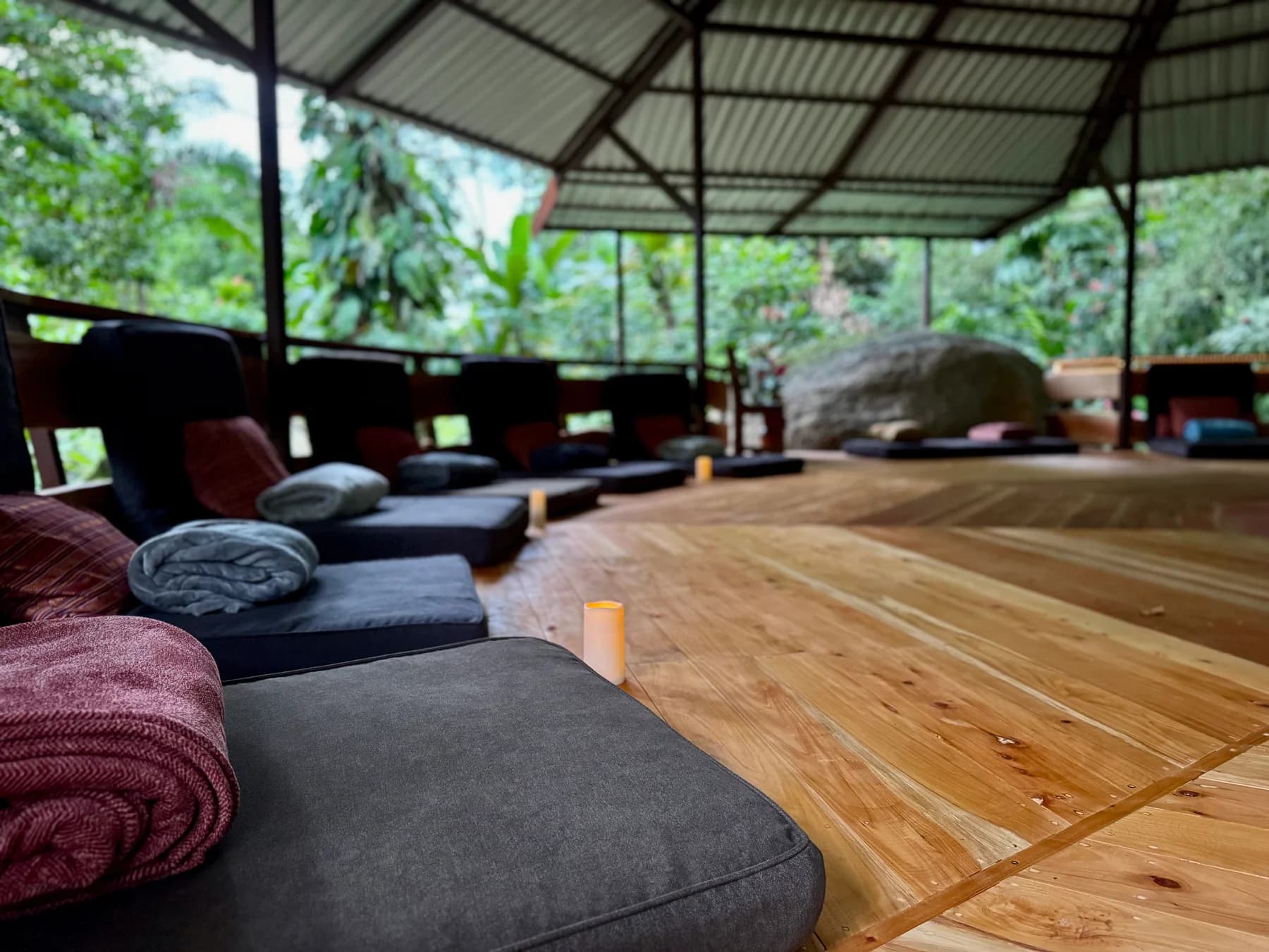 Open-air ceremony deck arranged with floor cushions and candles at Posada Natura